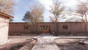 un bâtiment en briques avec des arbres devant lui dans l'établissement Hotel Casa Don Esteban, à San Pedro de Atacama