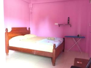 a bedroom with a bed with a pink wall at Standard Room (Pakej G1) in Semporna