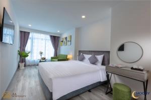 a bedroom with a large white bed and a mirror at Nha Trang Moony Hotel in Nha Trang