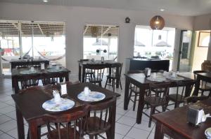 um restaurante com mesas e cadeiras de madeira e janelas em Marinas de Tamandaré 102 em Tamandaré
