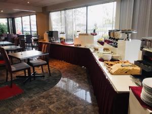 a restaurant with a counter with tables and chairs at Auckland Airport Kiwi Hotel in Auckland