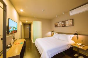 a hotel room with a bed and a flat screen tv at Jinjiang Inn Select Kunming South Railway Station University Town in Huacheng
