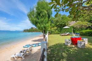 a beach with two white chairs and a tree at The Emerald Hill Beach Villa in Mae Nam