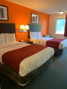 two beds in a hotel room with orange walls at Americas Best Value Inn - Fredericksburg North in Fredericksburg