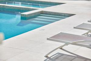 una piscina con una silla frente a ella en Hotel Ilusion Moreyo - Adults Only, en Cala Bona