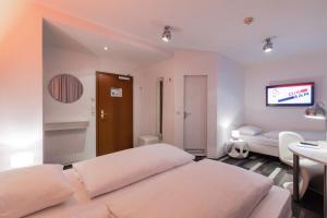 a bedroom with two beds and a tv on the wall at Cityhotel Monopol in Hamburg