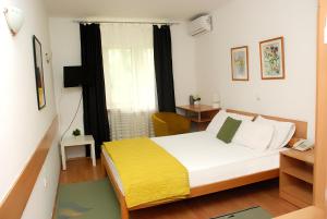 a bedroom with a bed with a yellow blanket at Hotel 7 in Skopje
