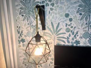aendant light hanging from a wall with floral wallpaper at ROOM 10 in Valmiera
