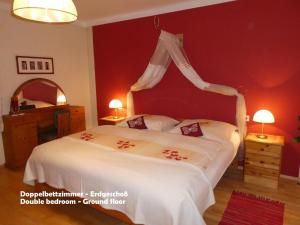 a bedroom with a white bed with a red wall at Gästehaus am Weinberg - Schlager in Prinzersdorf