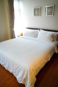 a large white bed in a bedroom with a window at Siam Bright Suite in Bangkok
