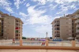 a white fence in front of two tall buildings at Apartment Sunny La Mata (VIÑAMAR VII) in La Mata