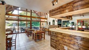 un restaurante con paredes de madera, mesas y sillas en Vacancéole - Le Village des Oiseaux, en Motz