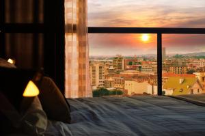 a bed in a room with a view of a city at Grand Appart'Antaninarenina in Antananarivo