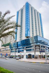 un gran edificio alto con coches estacionados frente a él en Novel Hotel City Center, en Abu Dabi