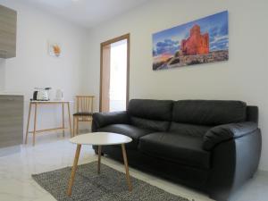 sala de estar con sofá negro y mesa en Pepprina Apartment by SeaStays 1 minute to Seafront, en St Paul's Bay