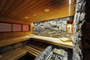 a sauna with a stone wall and wooden ceilings at Eiger Selfness Hotel**** - Zeit für mich in Grindelwald