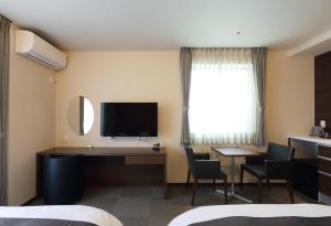 a hotel room with a desk and a television at HOTEL PROMOTE HIROSHIMA in Hiroshima