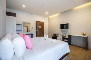 a bedroom with a white bed with pink pillows at U- Homehotel Nakhonpanom in Nakhon Phanom