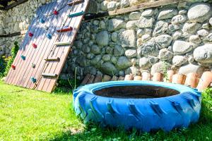 a blue tire in the grass next to a rock wall at Banskovilla Zlateva House in Bansko