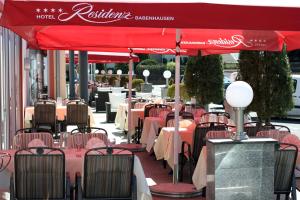 Hotel Residenz Babenhausen - Superior في بابينهاوزن: صف من الطاولات والكراسي تحت مظلة حمراء