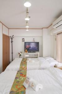 1 dormitorio con 3 camas blancas y TV de pantalla plana en sakura house, en Tokio