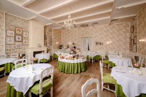 un comedor con mesas blancas y sillas verdes en Hotel Imperial & Champagne SPA, en Abrau-Dyurso