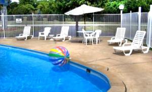 una piscina con una pelota de playa, sillas y una sombrilla en Monticello Inn - Monticello, Indiana en Monticello