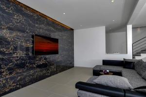 BastにあるHoliday home Eのソファと壁掛けテレビのあるリビングルーム