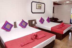 two beds in a hotel room with red sheets at Viva Guest House in Panaji