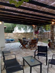 um pátio com uma mesa e cadeiras sob uma pérgula de madeira em Villa Glaykos em Thymonia Beach