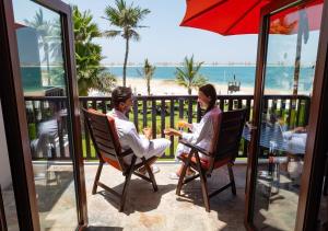 two people sitting in chairs on a balcony with the beach at JA Palm Tree Court (JA The Resort) in Dubai