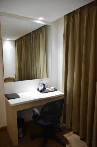 a desk in a room with a mirror and a chair at Hotel Radiance in Bareilly