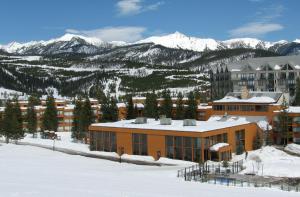 a building in the snow with mountains in the background at Huntley Lodge at Big Sky Resort in Big Sky