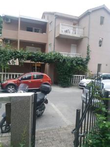 een rode auto geparkeerd op een parkeerplaats naast een gebouw bij Apartments Kordic in Budva