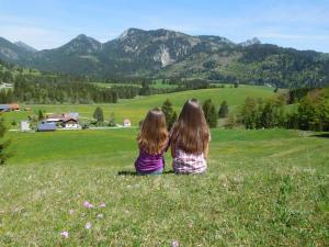 two girls sitting in a field looking at the mountains at Landhaus Panorama in Bad Hindelang