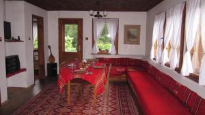 a red couch in a living room with a table at Villa Lyutovi Holiday Home in Koprivshtitsa