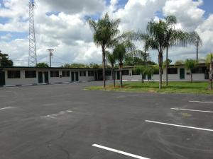 a parking lot with a large white building at Economy Inn Okeechobee in Okeechobee