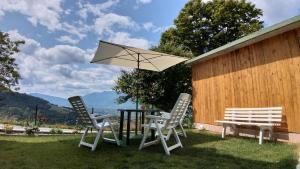 2 Stühle und ein Tisch mit einem Regenschirm und einer Bank in der Unterkunft Casa Verde Belluno in 