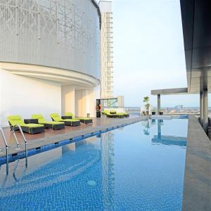 a swimming pool with yellow chairs next to a building at Midtown Residence Surabaya in Surabaya