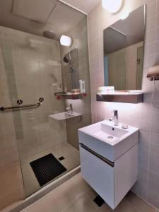 a bathroom with a shower and a sink and a mirror at Jinjiang Inn Select Kunming South Railway Station University Town in Huacheng