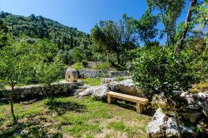 a wooden bench sitting in the grass near some rocks at Apartments Korita in Maranovići