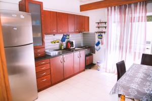 a kitchen with wooden cabinets and a stainless steel refrigerator at Comfortable House with Warm Hospitality in Katerini