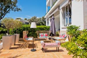 a patio with chairs and a table and an umbrella at Hôtel La Villa Cap d’Antibes in Juan-les-Pins