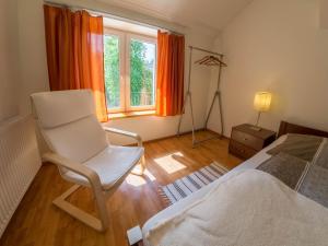 a bedroom with a white chair next to a bed at Apartament Zdrojowy in Lądek-Zdrój