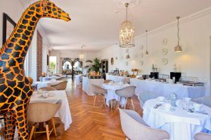 a giraffe statue in a restaurant with tables and chairs at Hôtel La Villa Cap d’Antibes in Juan-les-Pins