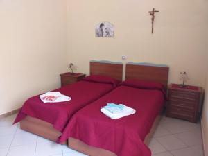 1 dormitorio con 1 cama con sábanas rojas y una cruz en la pared en Santa Maria Maddalena, en Nápoles