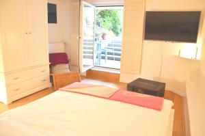 Schlafzimmer mit einem Bett, einem TV und einem Balkon in der Unterkunft Gästezimmer mit Garten in Fischeln in Krefeld