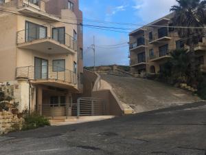 an empty street in front of two apartment buildings at Kantra Residence in Xlendi