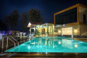 una piscina di fronte a una casa di notte di Four Vedas Hotel & Resort a Siliguri