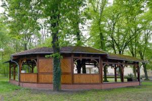 un cenador de madera en un parque con un árbol en Hostel in Guben, en Guben